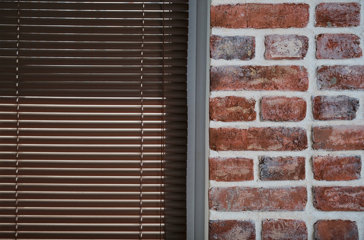 Window with brown blinds and a brick wall made of old bricks, loft interior, industrial interior as a background, close-up